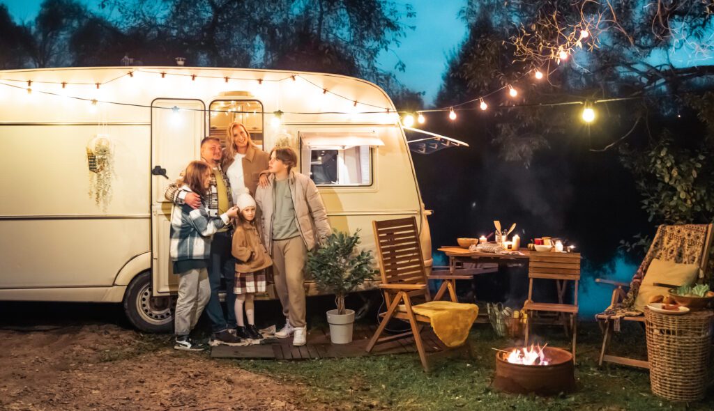 Family trailer travel. Evening with garland. Children,brother sister,mom dad.Picnic in