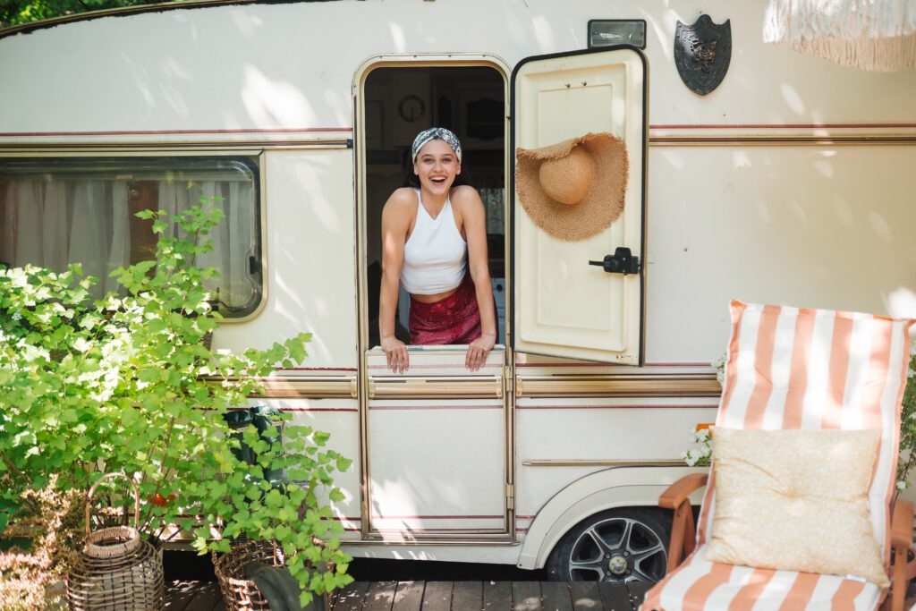 Happy hippie girl is having a good time in a camper trailer. Holiday, vacation, trip concept.