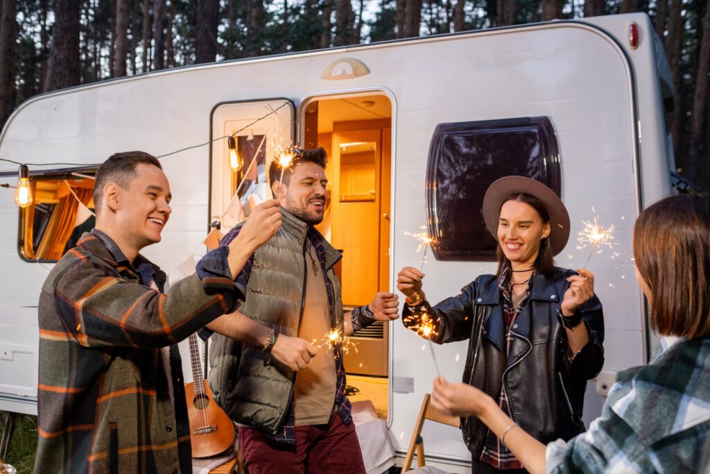 Young joyful friends dancing with sparkling bengal lights
